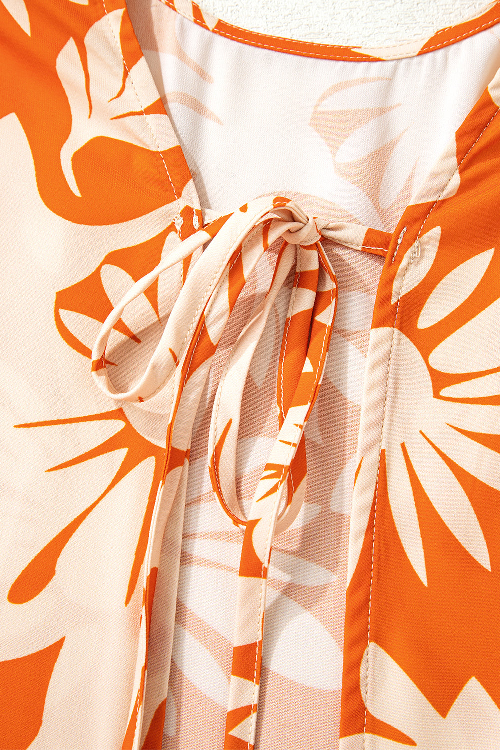 Blusa naranja de manga larga con estampado floral, nudo y espalda abierta