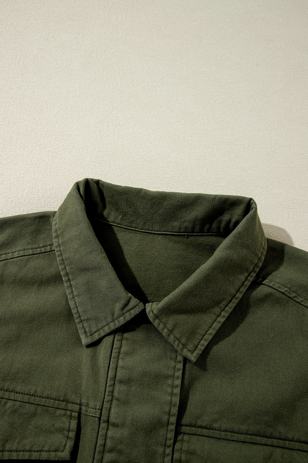 Chaqueta color verde musgo con cremallera, botones a presión, cintura ajustada y cuello.
