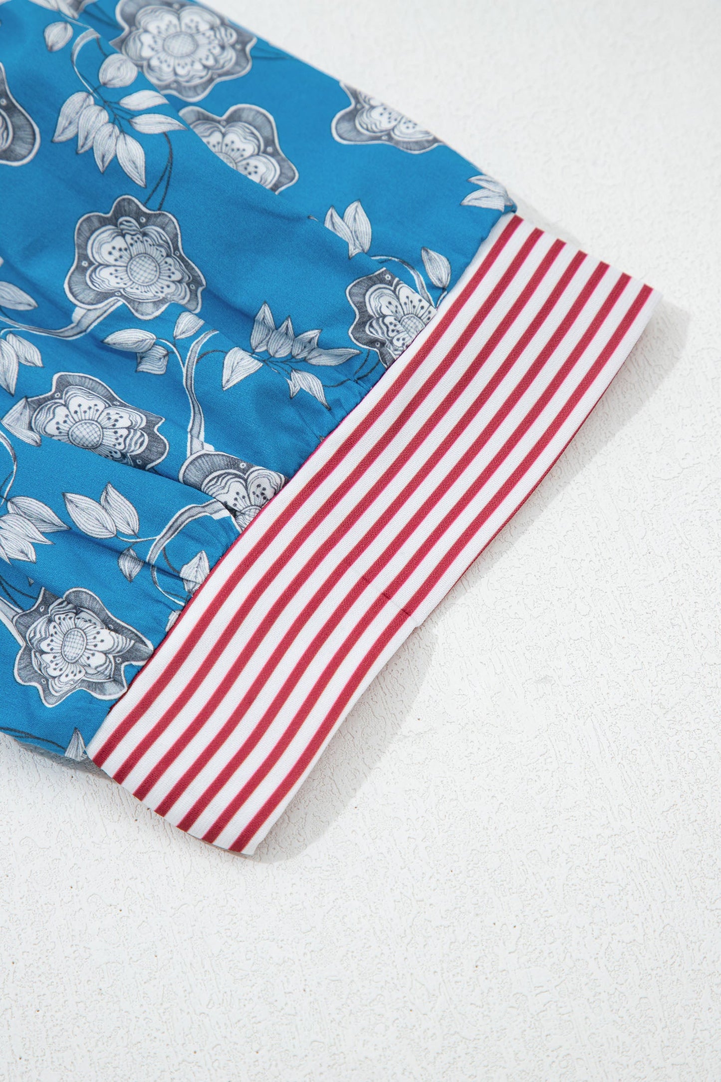 Blusa de manga corta con cuello abotonado, ribete a rayas y estampado floral retro azul