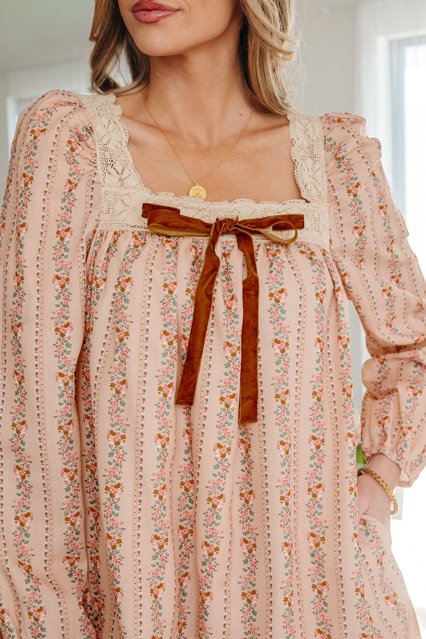 Minivestido suelto de manga larga con estampado floral caqui, lazo de terciopelo en contraste y encaje.