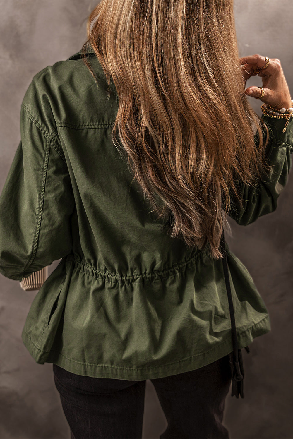 Chaqueta color verde musgo con cremallera, botones a presión, cintura ajustada y cuello.