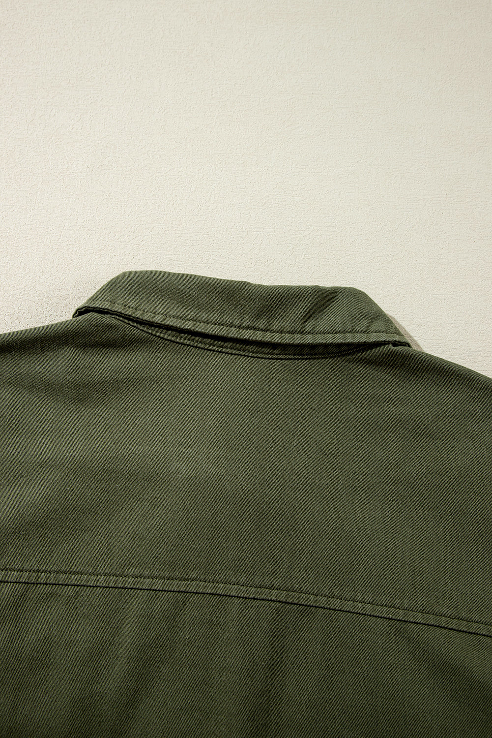 Chaqueta color verde musgo con cremallera, botones a presión, cintura ajustada y cuello.