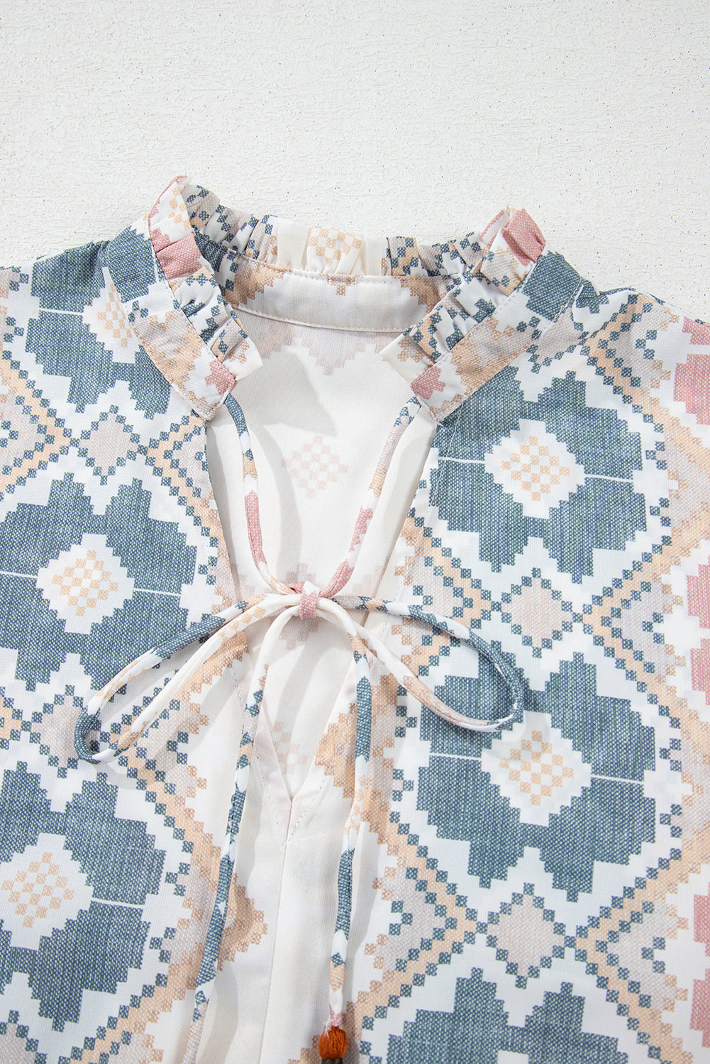 Blusa caqui con estampado geométrico, cuello dividido con lazo de borlas y mangas globo