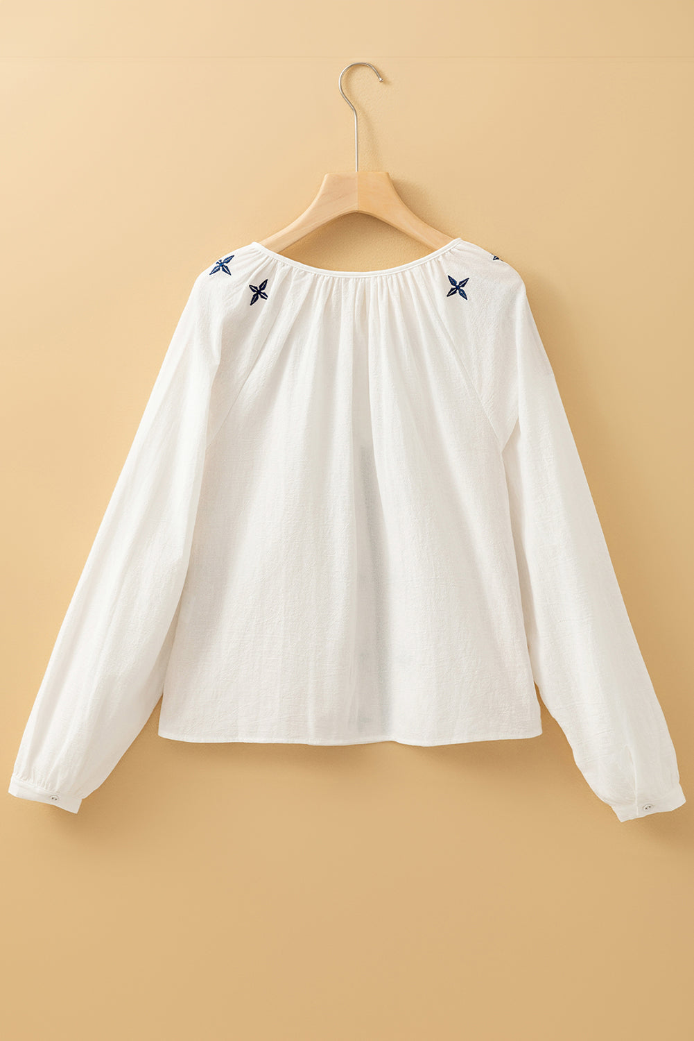 Blusa blanca con bordado geométrico, manga larga y botones