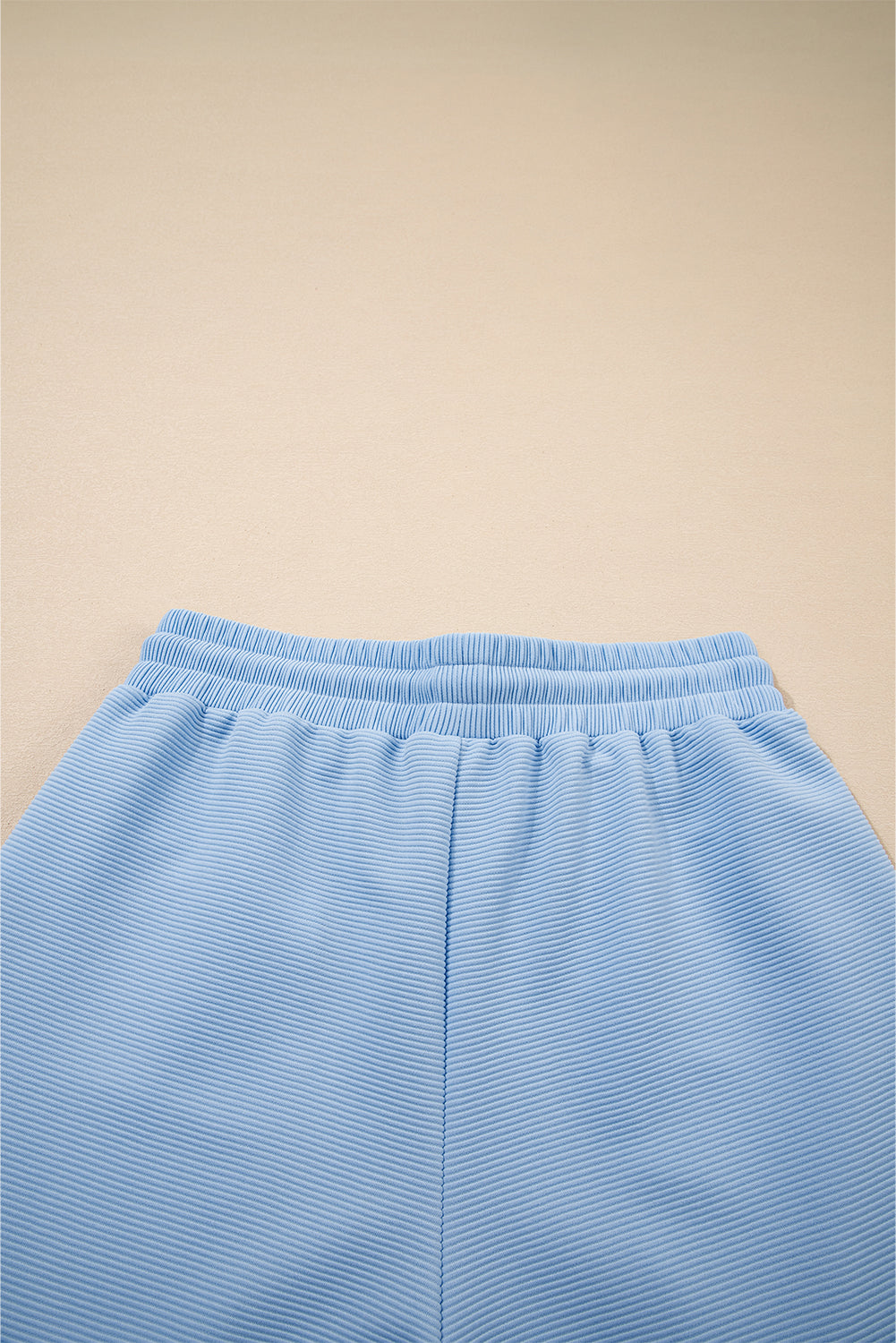 Conjunto de top con cremallera, mangas con volantes y textura azul cielo, y pantalón de pernera ancha
