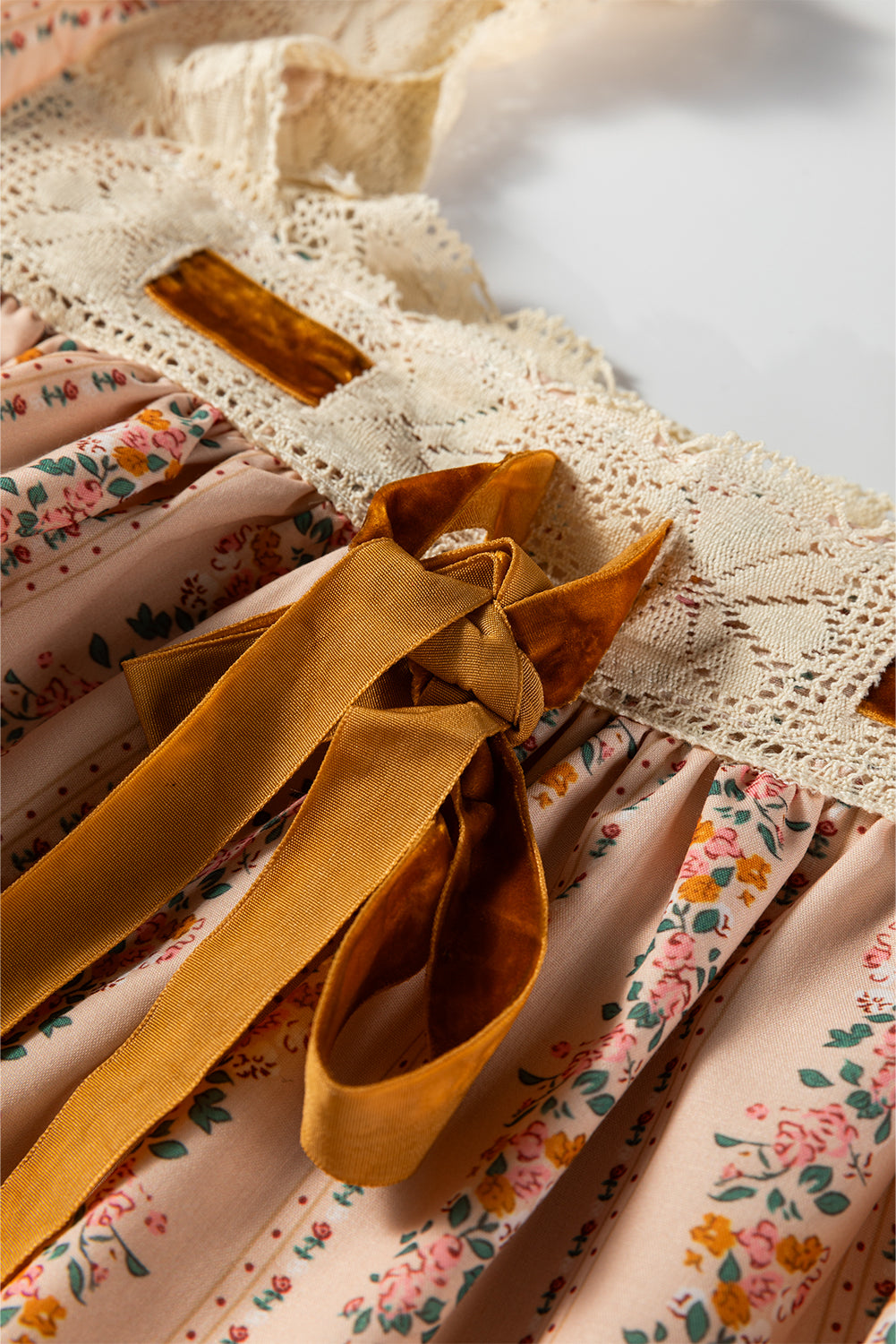 Minivestido suelto de manga larga con estampado floral caqui, lazo de terciopelo en contraste y encaje.