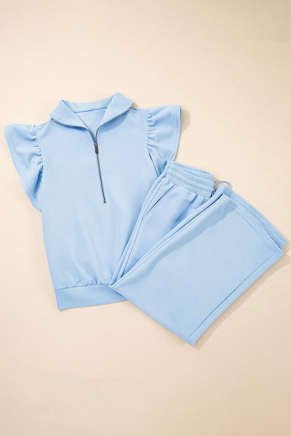 Conjunto de top con cremallera, mangas con volantes y textura azul cielo, y pantalón de pernera ancha