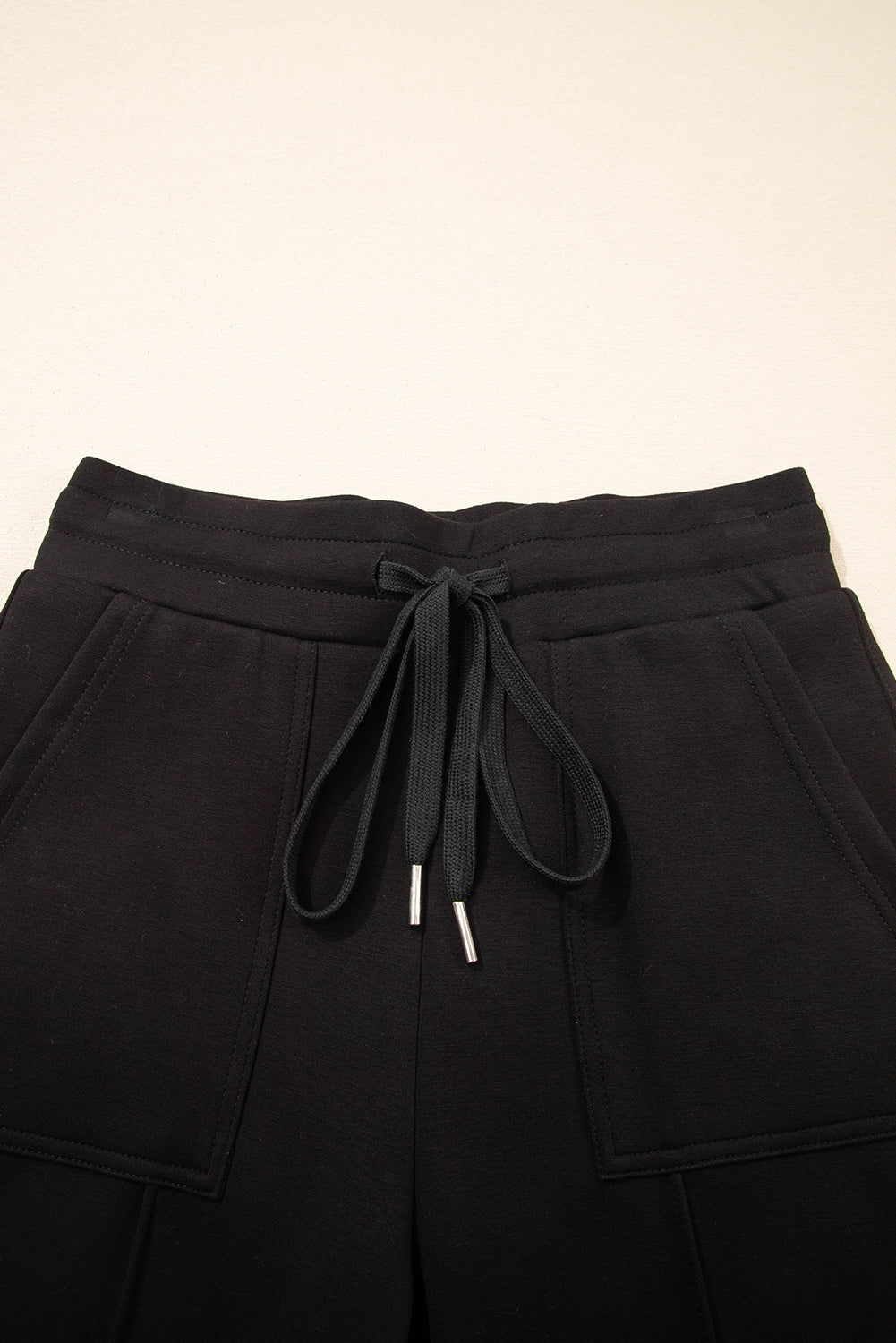 Pantalones joggers pitillo con cordón y detalles de costura expuesta, en color negro