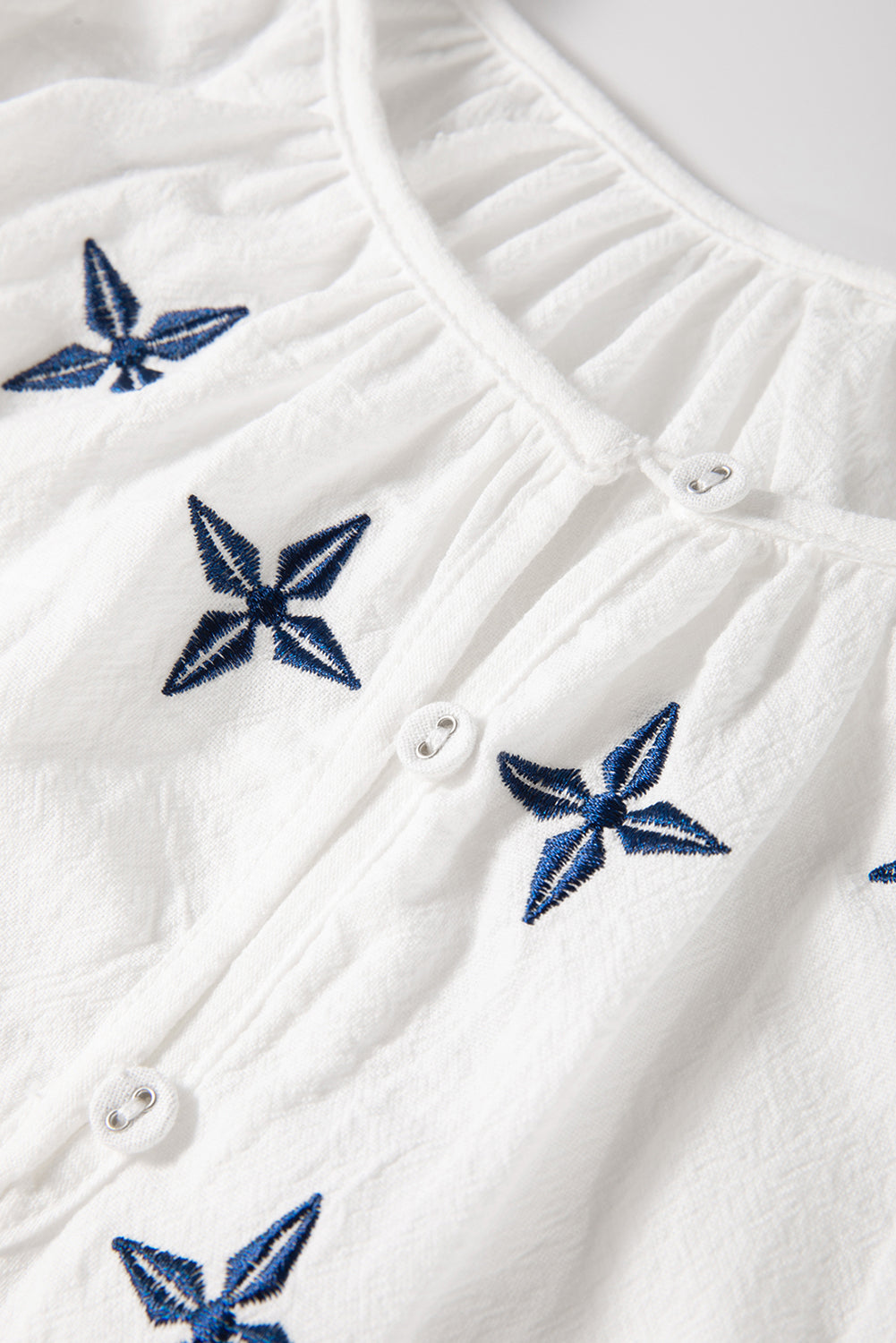 Blusa blanca con bordado geométrico, manga larga y botones