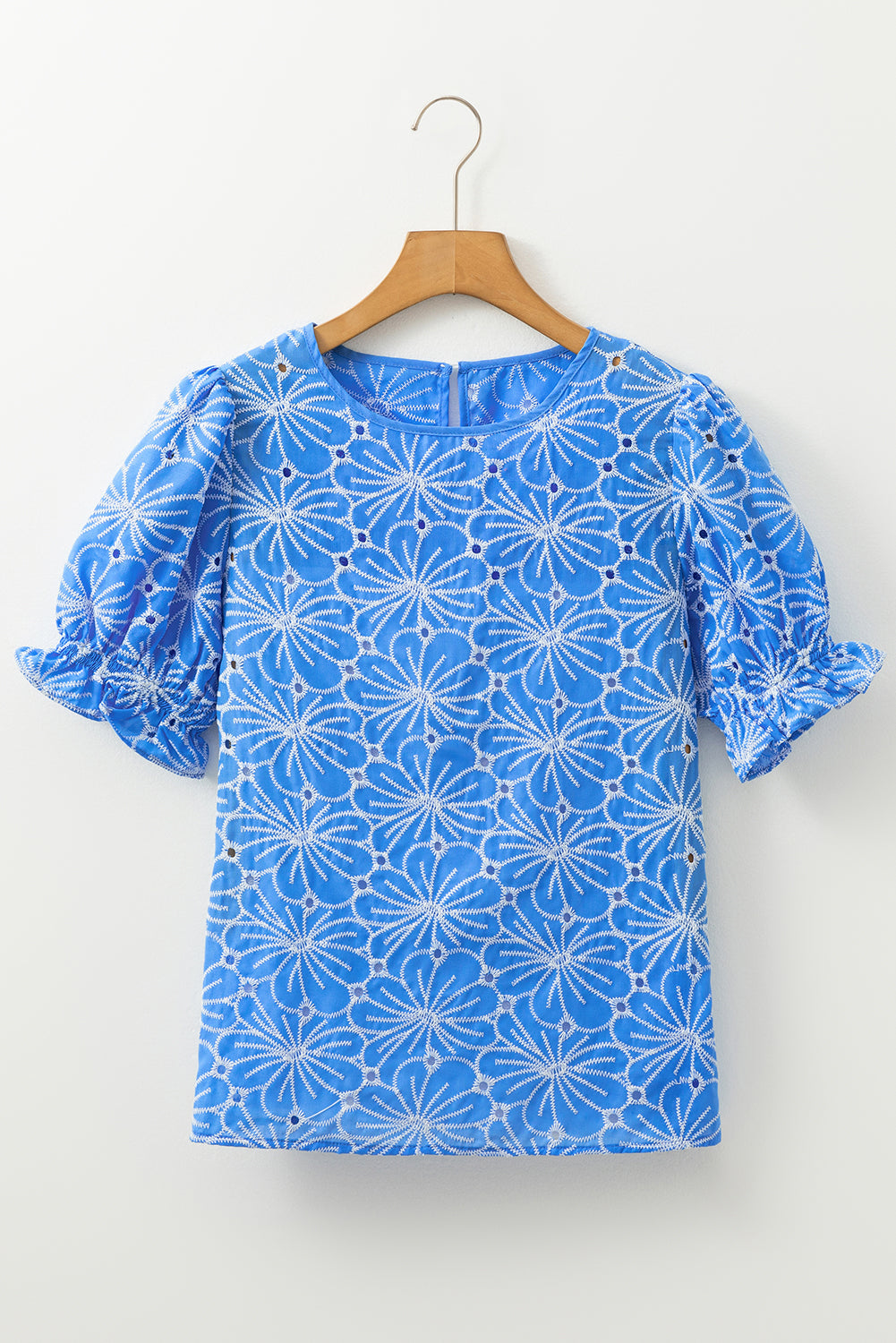 Blusa celeste con bordado de flores, ojales y manga corta abullonada con volantes