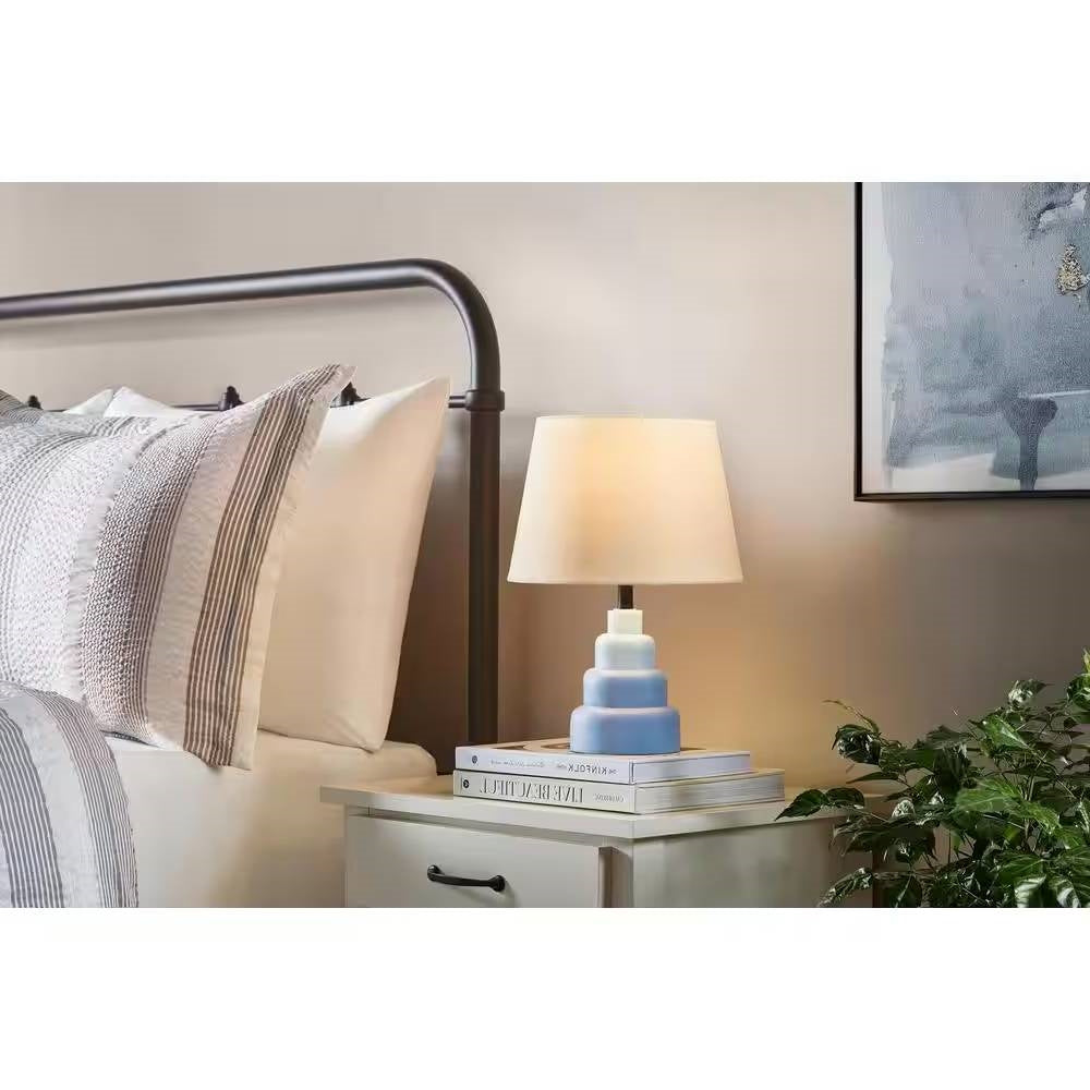 Pequeña lámpara de mesa azul con pantalla de tela blanca para mesita de noche