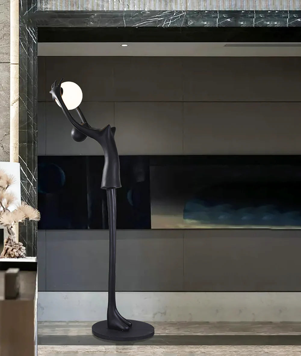 Lámpara de pie con personaje de escultura que sostiene una pelota