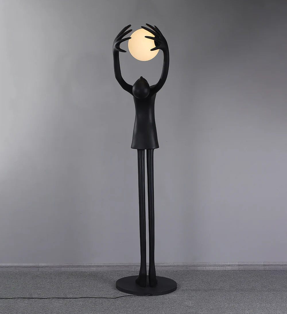 Lámpara de pie con personaje de escultura que sostiene una pelota