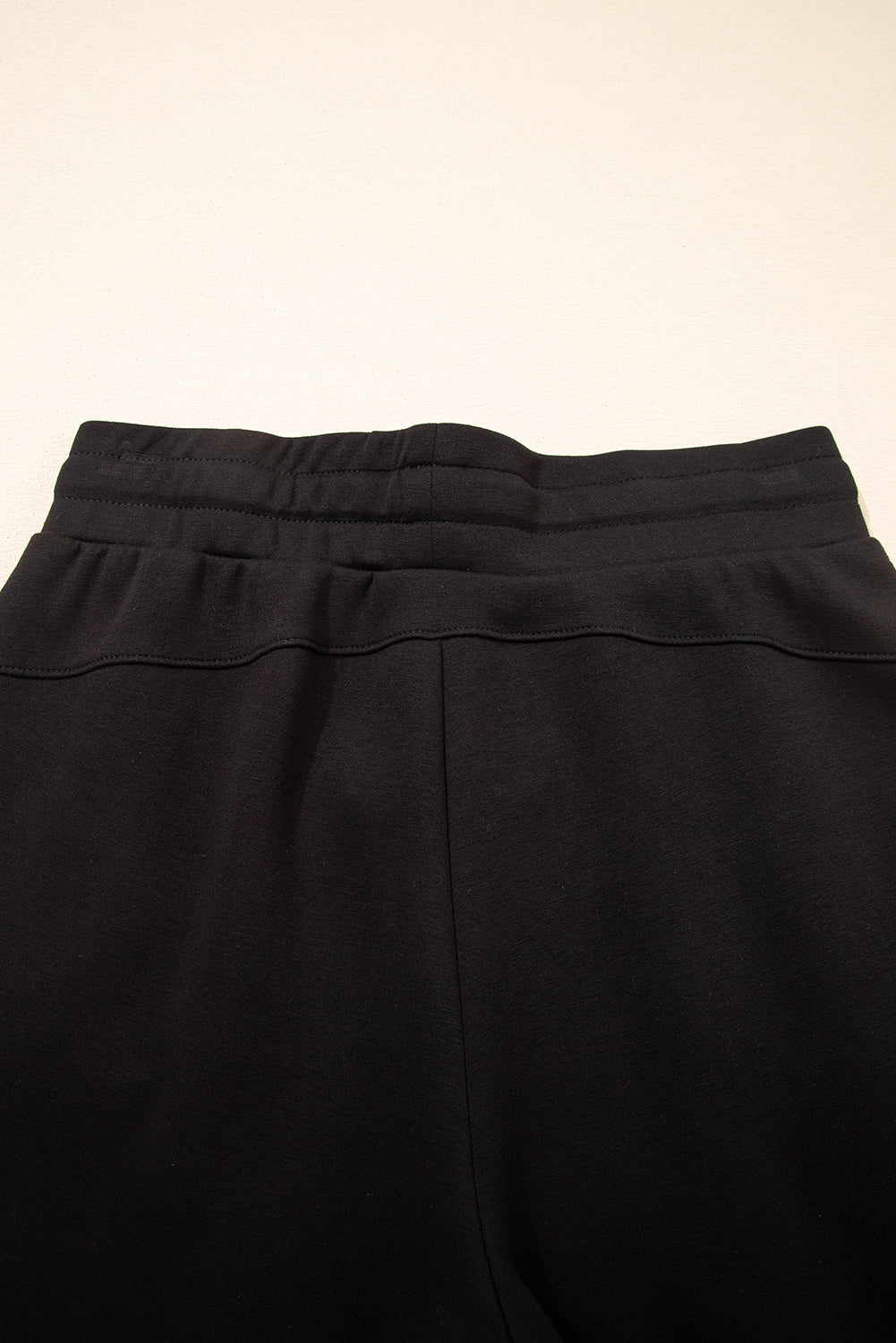 Pantalones joggers pitillo con cordón y detalles de costura expuesta, en color negro
