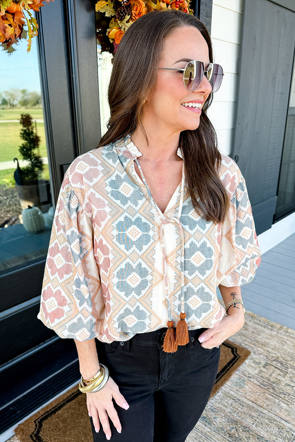 Blusa caqui con estampado geométrico, cuello dividido con lazo de borlas y mangas globo