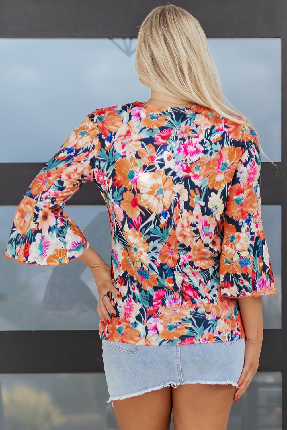 Blusa negra floral con manga 3/4 acampanada y cuello de pico con lazo