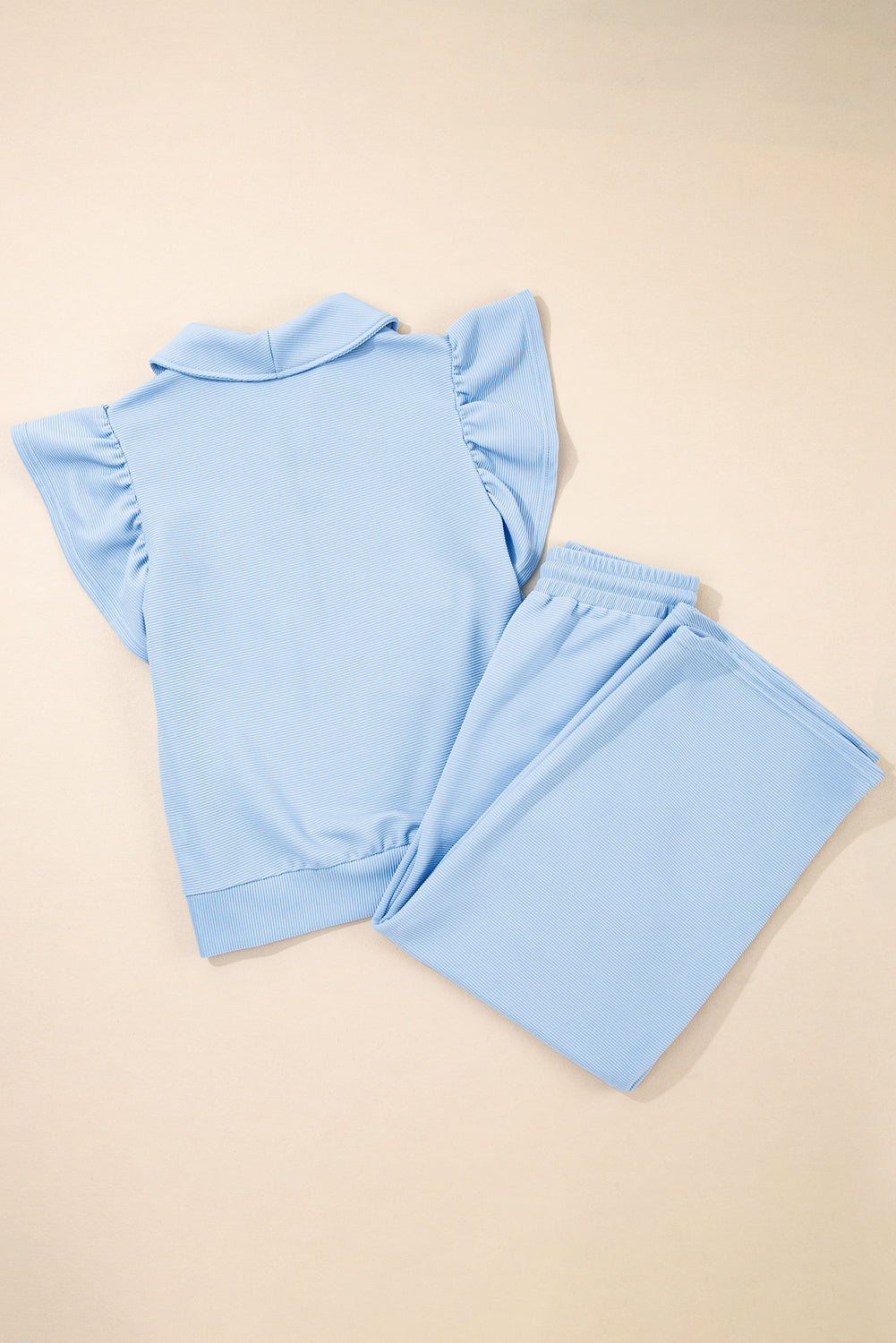 Conjunto de top con cremallera, mangas con volantes y textura azul cielo, y pantalón de pernera ancha