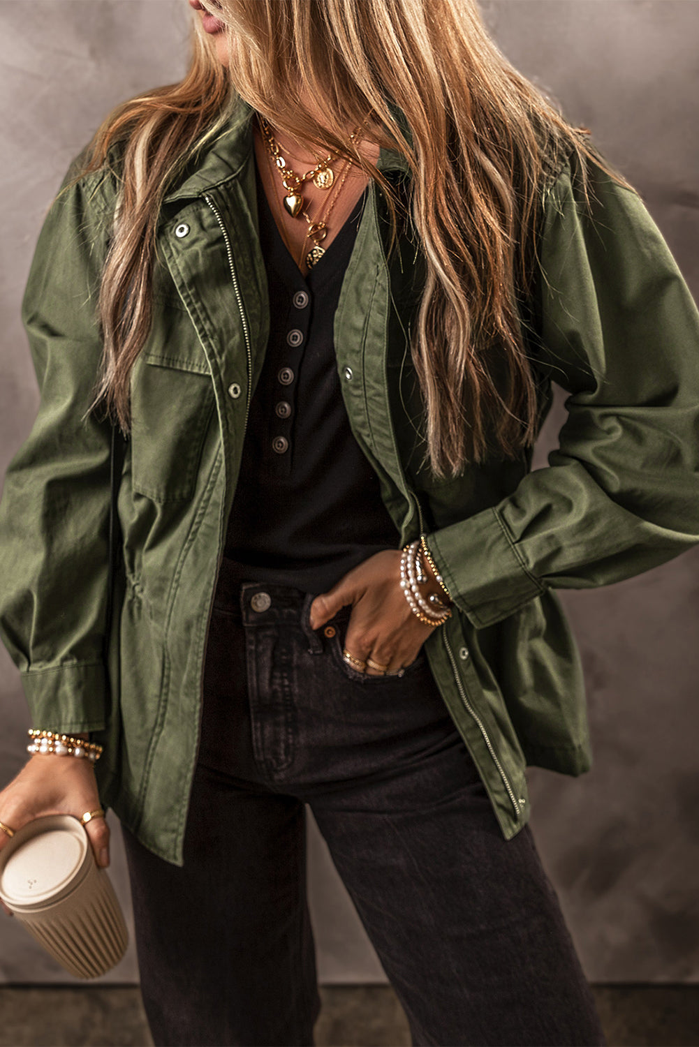 Chaqueta color verde musgo con cremallera, botones a presión, cintura ajustada y cuello.