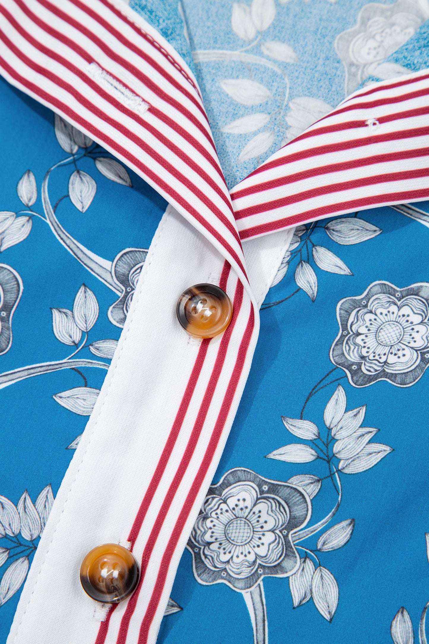 Blusa de manga corta con cuello abotonado, ribete a rayas y estampado floral retro azul
