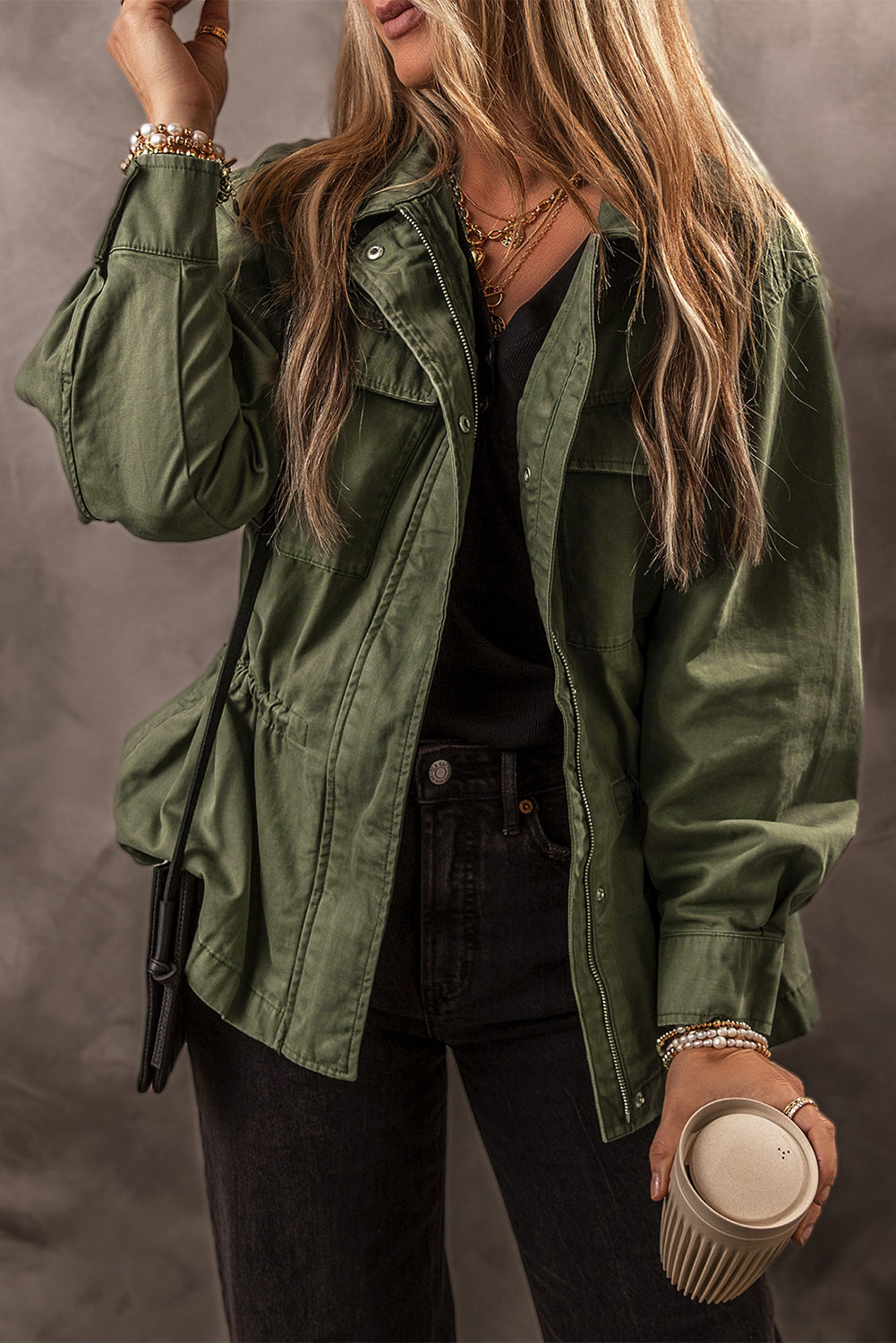 Chaqueta color verde musgo con cremallera, botones a presión, cintura ajustada y cuello.