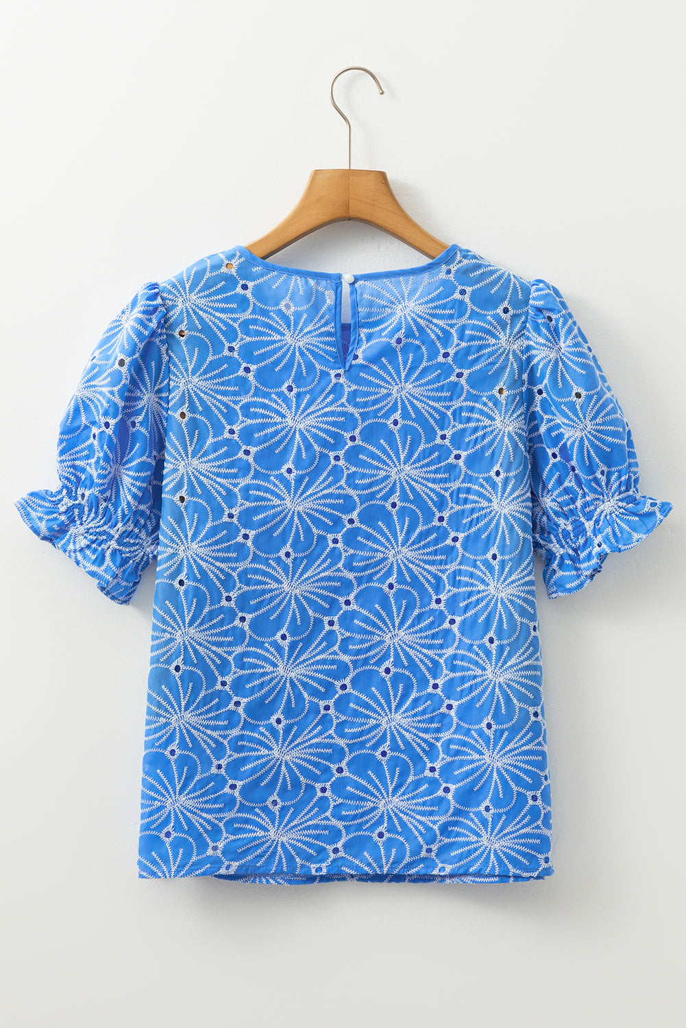 Blusa celeste con bordado de flores, ojales y manga corta abullonada con volantes