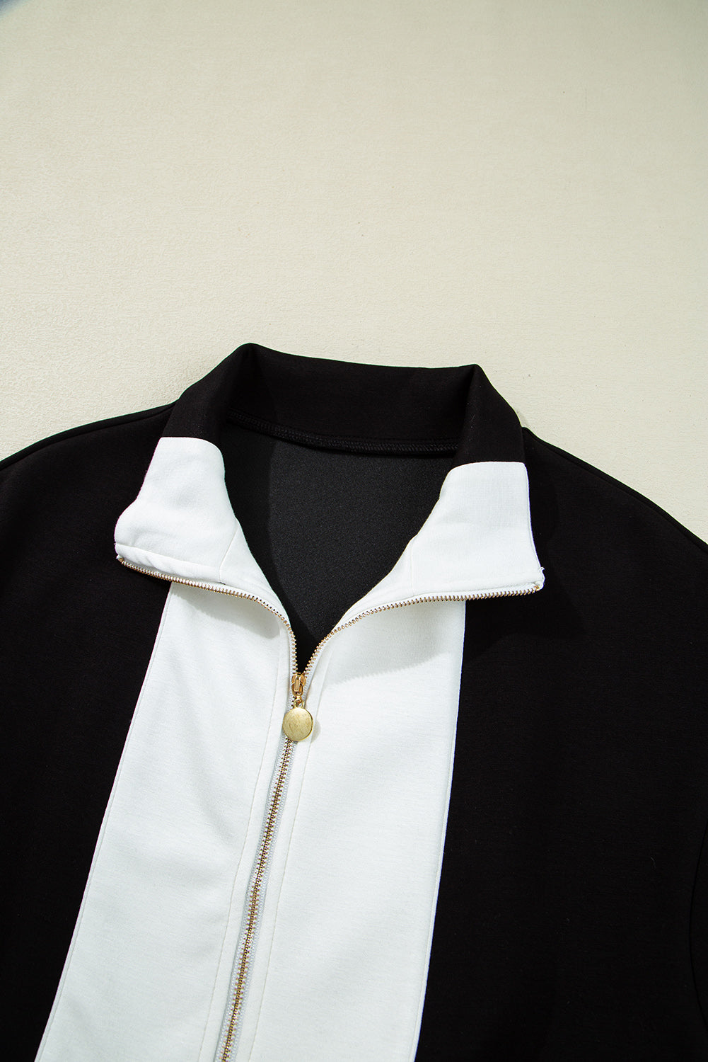 Mono corto negro con cuello en contraste, retales y cremallera frontal