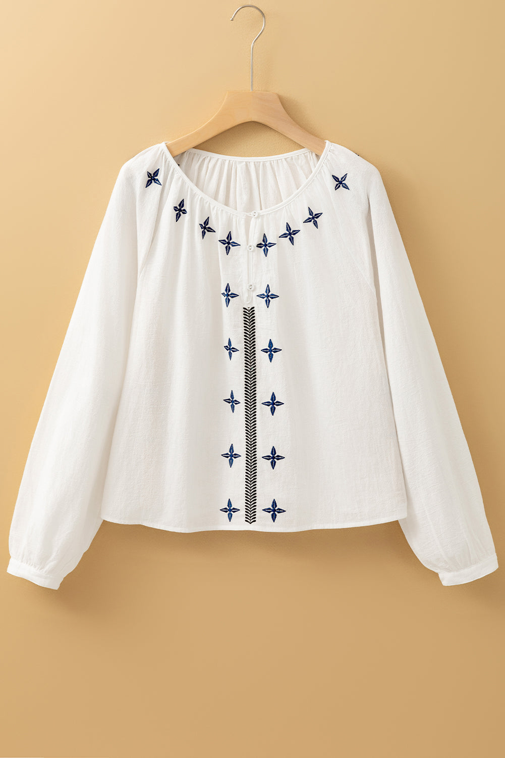 Blusa blanca con bordado geométrico, manga larga y botones