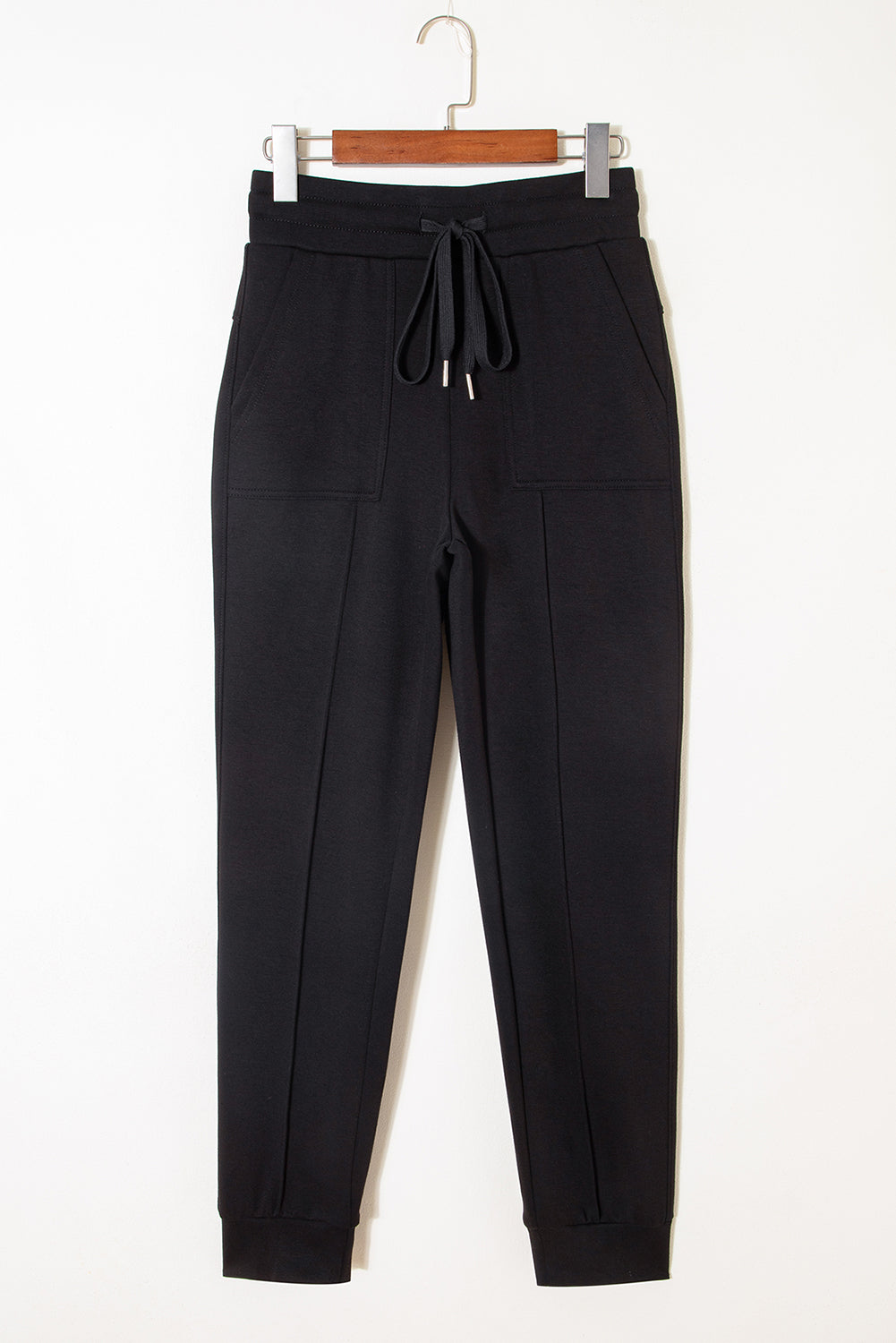 Pantalones joggers pitillo con cordón y detalles de costura expuesta, en color negro